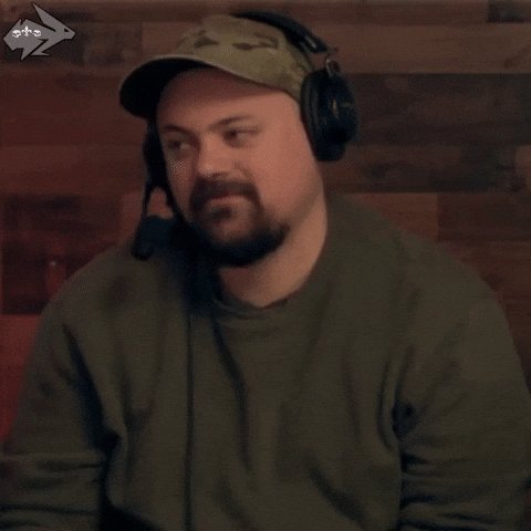 The image features a man wearing a green sweatshirt, a hat with headphones, and a serious expression as he looks off into space or at something else that has caught his attention. The caption of the image reads "this is wild as hrllflipping alien flamethrowers into pcb designs that hit mars? my guy is out here living the sci-fi future for real".