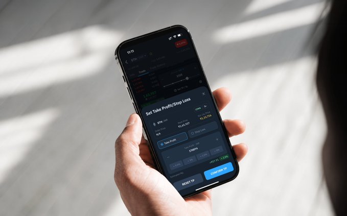 The image shows a person holding a smartphone displaying a trading app interface with a "Set Take Profit/Stop Loss" screen, where ETH (~$3,394) is being traded with TP/SL settings around $3,400, directly reinforcing the caption's message about pre-planning exits. The screen illustrates the practical execution of disciplined trading—setting profit-taking and loss-limiting orders before emotions take over.