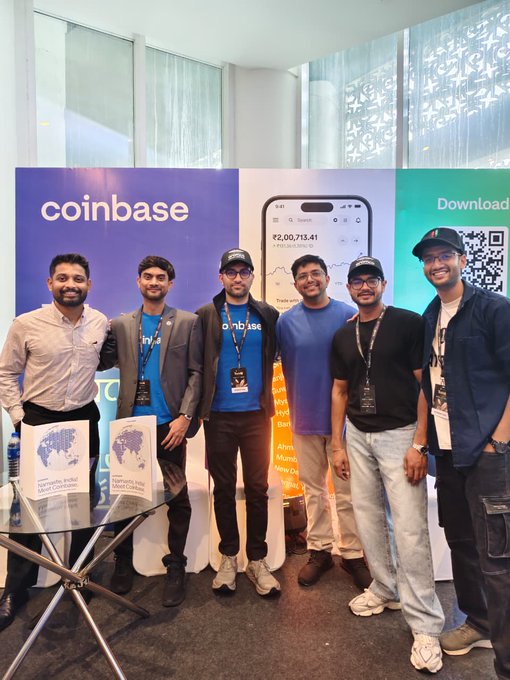 A group of six smiling individuals pose together at a Coinbase promotional booth, with the company's logo and a display showing ₹2,00,713.41 on a smartphone screen visible behind them, along with books titled "Karmayogi: India Talent Exchange" on a table—reflecting Coinbase's recent visit to Kolkata's TradeIQ event as part of their efforts to expand crypto exchange services in India.