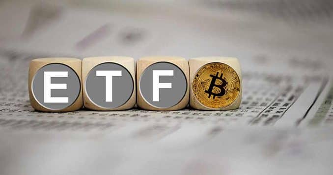 Wooden dice spelling 'ETF' sit next to a golden Bitcoin coin on a surface with blurred financial numbers in the background, representing Bitcoin ETFs.
