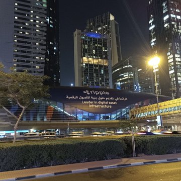A nighttime cityscape in Dubai features a large illuminated Ripple advertisement displayed on the side of a building, with the bilingual text "Ripple" and "Leader in digital Asset Infrastructure" visible in both English and Arabic. The prominent branding placement in this major financial hub aligns with the post's message about Ripple's growing global presence and XRP's expanding visibility as a leading digital asset.