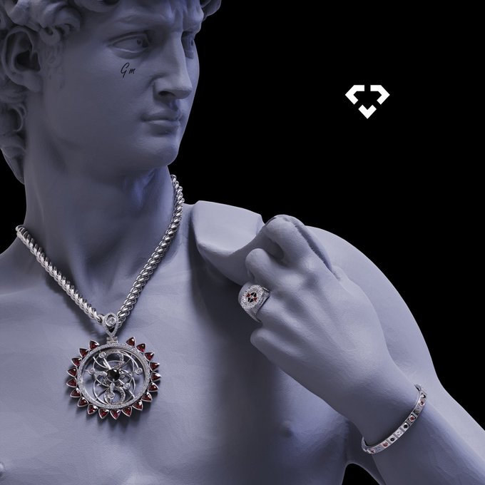 A statue-like figure rendered in blue tones wearing silver jewelry including a chain with a pendant, a ring, and a bracelet, with a small heart-shaped logo visible in the upper right against a black background.