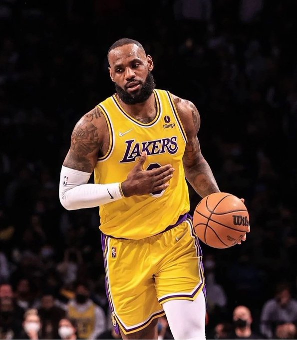 NBA player LeBron James in a yellow Lakers jersey dribbling a Wilson basketball during a game.