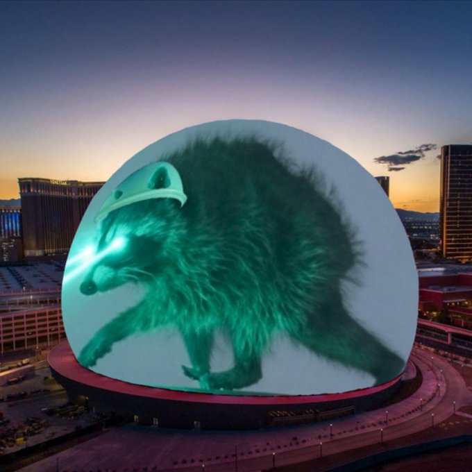 An image of the Las Vegas Sphere displaying a large, glowing green hedgehog-like creature wearing a white helmet.