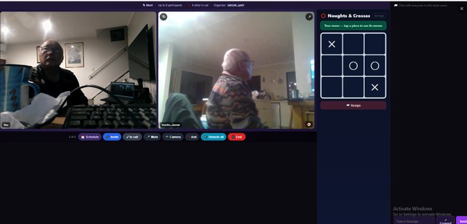 The image shows a video chat interface with two participants engaged in a "Noughts & Crosses" (tic-tac-toe) game on BSVBSV.com, as evidenced by the tic-tac-toe board on the right side with X's and O's placed. The participants appear to be playing the simple face-to-face game described in the post, demonstrating the platform's ability to facilitate live, video-enabled board games.