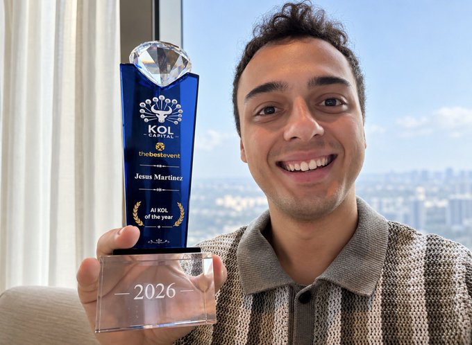 A smiling young man proudly holds a blue and crystal 'KOL CAPITAL' trophy inscribed with 'thebestevent', 'Jesus Martinez', and 'AI KOL of the year 2026'.