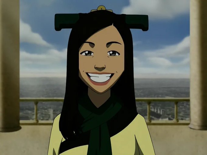 An animated character with long black hair wearing a green and yellow outfit smiles broadly, with a cityscape visible through a window behind her.