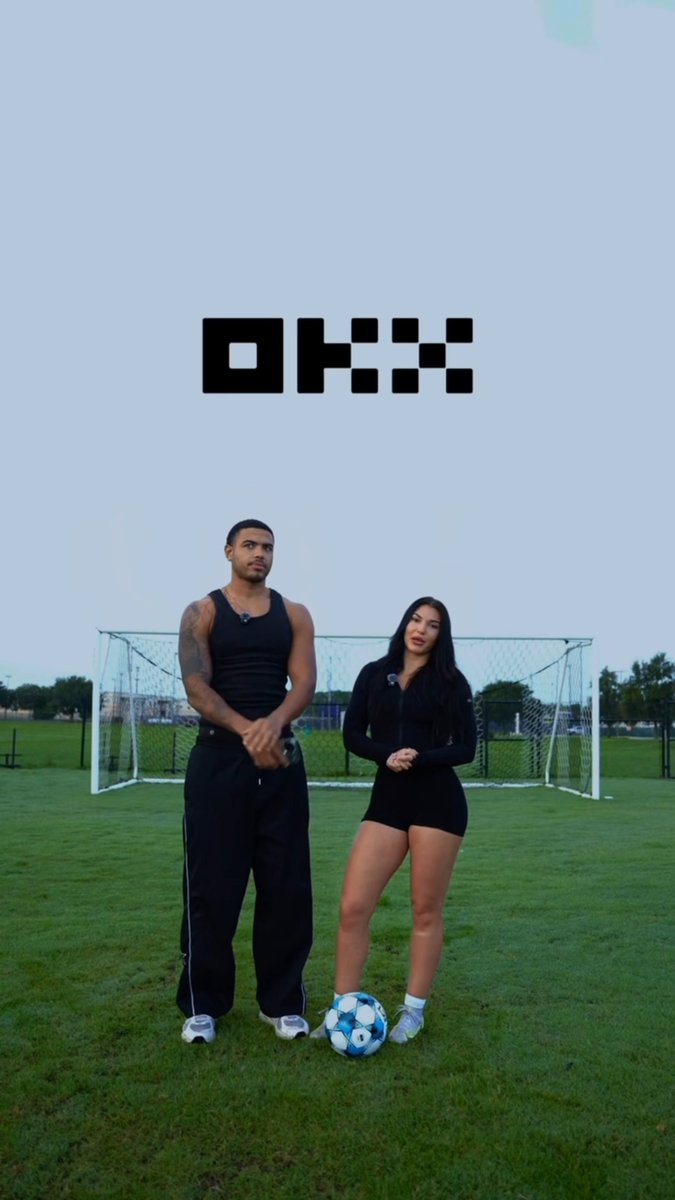 A man in a black tank top and a woman in black athletic wear stand on a soccer field in front of a goal with a soccer ball at their feet, beneath a large "OKX" logo. The image ties to the post's promotion of OKX's "Big Game" prediction feature, where users can bet on soccer match outcomes for a chance to win Bitcoin rewards.