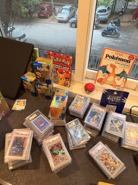 A collection of Pokemon trading card game booster packs, cereal boxes, and sealed card stacks displayed on a table near a window.