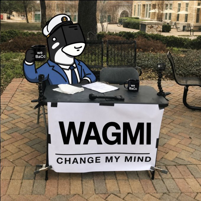 A cartoon illustration of a dog-like character in a sailor outfit sitting at a desk with a sign reading 'WAGMI CHANGE MY MIND', holding a 'we BaCC' mug and raising a finger in the air.