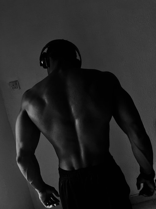 The image features a man with headphones, standing against a white wall. The man has his back turned towards the camera, wearing black pants that are visible from behind. There's also an element of humor present as there is a caption that reads "Focus on what is in the image and how it relates to the post".