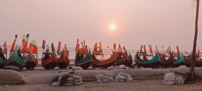 The image features a beach scene with several boats docked near the shoreline. The boats are painted in various colors, including green, red, blue, and orange. They appear to be empty or waiting for passengers. The sun is setting behind the boats, creating a beautiful backdrop that highlights their vibrant colors against the sky. The image also contains text elements such as "Good afternoon Fam." and "@TheARCorterMinal," which may provide additional context about the location or the people involved in this beach scene.