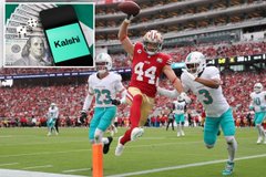 A football player in a red jersey with number 44 reaches up to catch a football during a game, with opposing players in teal jerseys nearby and a 'kalshi' logo in the upper left corner.