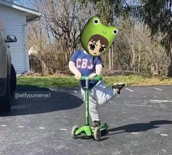 A humorous edited image of a child riding a green scooter in a driveway, wearing a CBS shirt with their face replaced by a cartoon anime character and a giant green frog hat.