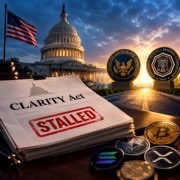 An illustration features a 'CLARITY Act' document stamped with red 'STALLED' text, surrounded by various cryptocurrency coins and the US Capitol building under a dramatic sky.