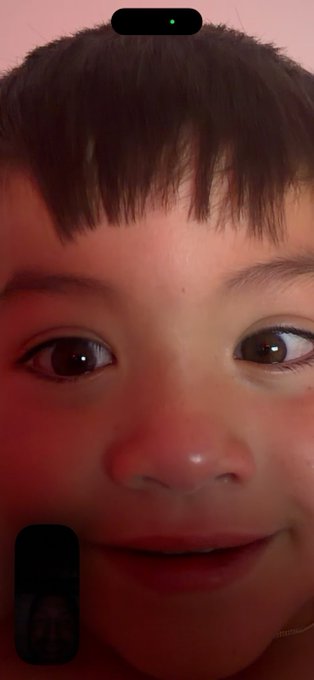 A close-up selfie of a young person with short dark hair and bangs, with the phone's front camera notch visible at the top of the frame.