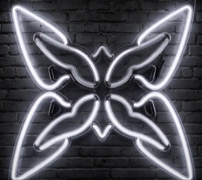 A symmetrical neon sign shaped like a butterfly is illuminated in bright white against a dark brick wall.