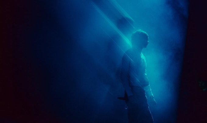 A silhouetted figure stands shrouded in deep blue haze and dramatic light rays, evoking a haunting, introspective stillness that mirrors the post's reflection on the weight of silence and the intimacy of collecting emotional moments as art.