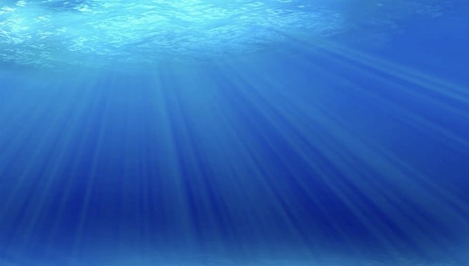 An underwater scene showing sunlight rays streaming down through blue ocean water.