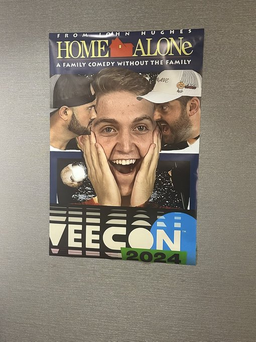 A parody movie poster titled 'HOME ALONE - A FAMILY COMEDY WITHOUT THE FAMILY' from John Hughes, branded with 'VEECON 2024', featuring a man's face being squeezed by two others.