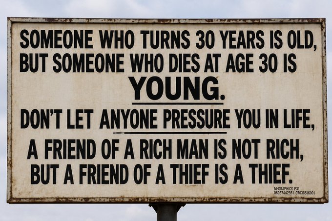 A weathered metal sign with text reading: "SOMEONE WHO TURNS 30 YEARS IS OLD, BUT SOMEONE WHO DIES AT AGE 30 IS YOUNG. DON'T LET ANYONE PRESSURE YOU IN LIFE, A FRIEND OF A RICH MAN IS NOT RICH, BUT A FRIEND OF A THIEF IS A THIEF."