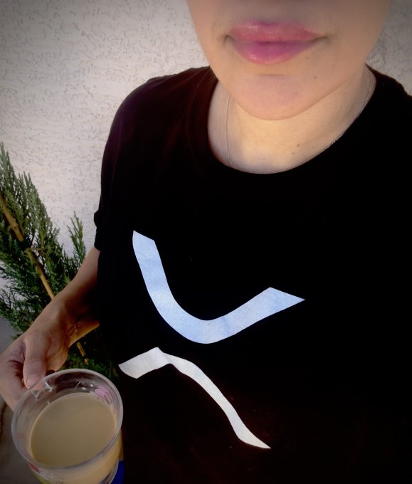 The image features a woman wearing a black t-shirt with white text that says "XRP". She is holding a cup of coffee, which has a logo for Bitcoin on it. The scene suggests that she might be discussing or promoting Bitcoin as a digital currency, possibly related to the XRP project.