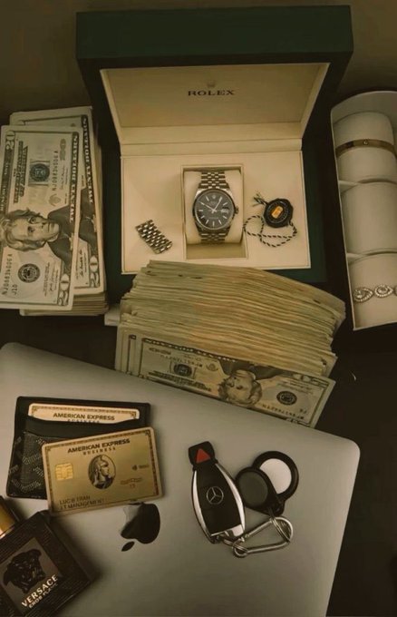 The image features a collection of luxury items, including a Rolex watch, a stack of money, an Apple wallet, and a car keychain. The objects are arranged on a table or desk, suggesting that they might be used for business purposes or as part of someone's daily routine. The post "life when once you fully believe in the art of wagmi" seems to be referring to the idea of accumulating wealth and material possessions, which is often associated with luxury items like Rolex watches, designer clothing, and expensive cars.