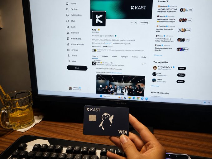 The image shows a person holding a Visa credit card over a computer monitor displaying a social media website. The focus of the image is on the technology behind the @KASTxyz Visa card, which has been successful in bridging stablecoins and global payments. The post highlights how stablecoins have proven themselves as one of the most successful applications of blockchain technology for users to transfer value quickly, at low cost, and without any central authority or middlemen.