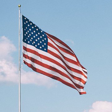 An American flag waves against a blue sky, symbolizing the political and legislative discussions happening on Capitol Hill. The flag serves as a fitting visual for crypto industry leaders meeting with Republican leadership to discuss the CLARITY Act, representing the regulatory and governmental developments shaping the future of digital assets.