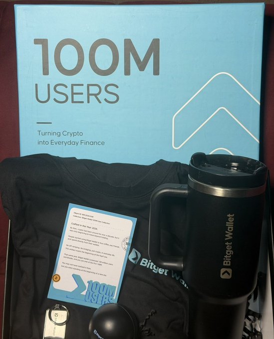 A Bitget Wallet promotional package celebrating "100M USERS - Turning Crypto into Everyday Finance," featuring a branded travel mug, t-shirt, and a congratulatory card. The image illustrates the post's joke about being a "washed KOL" since receiving such PR packages from crypto exchanges like Bitget has become a status symbol among crypto influencers.