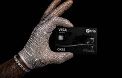 The image features a hand holding a Visa credit card, with the text "Visa" visible on the card itself. The background of the image is black, which contrasts with the white text on the card. The caption at the bottom of the image reads "made this video a while back reposting because tria is the future but you already knew that if you haven' t started using the card yet...".