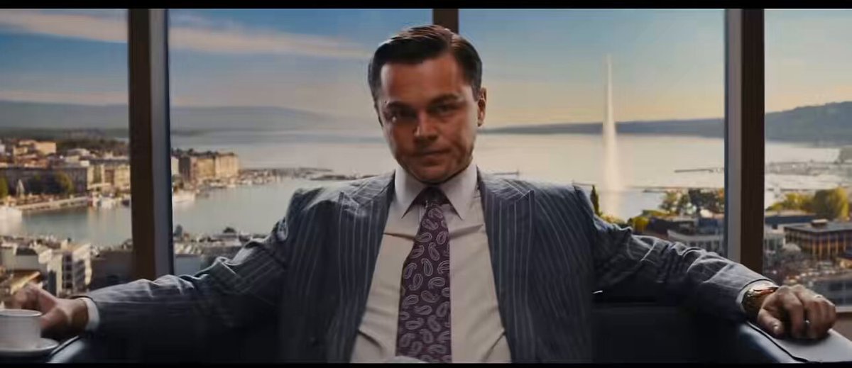The image features a man sitting in an office chair, wearing a suit and tie with his arms crossed over his chest. The background of the image shows a cityscape with buildings and water, suggesting that he might be in a high-rise building or near a waterfront. There is also text on the image that reads "Focus on what is in the image and how it relates to the post." This could indicate that the man's attire and setting are relevant to the discussion about AI and cryptocurrency.