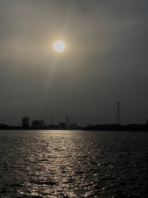 A glowing sun hangs low over a calm waterfront at dusk, casting shimmering reflections across the water while silhouetted city structures and power lines fade into the darkening horizon. The peaceful sunset mirrors the post's quiet "Good Night" mood, contrasting the stillness of day with the promise of Web3's always-on, decentralized future.
