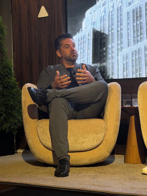 Ryan J. Alvarez, CEO of Vivabo, sits cross-legged in a yellow armchair during a panel discussion, gesturing thoughtfully as he discusses the importance of delivering value to subscribers and building customer loyalty. The image captures him mid-conversation in a professional speaking engagement setting, aligning with his quote about prioritizing customer value and loyalty.