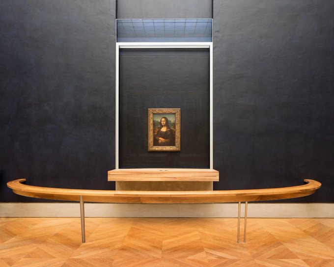 A polished wooden boat-shaped bench sits centered in the Louvre's Mona Lisa gallery. The image evokes a refined, museum-like atmosphere, suggesting that xrpcafe’s ongoing features are crafted with the same care, prestige, and thoughtful presentation as exhibits in iconic art institutions.