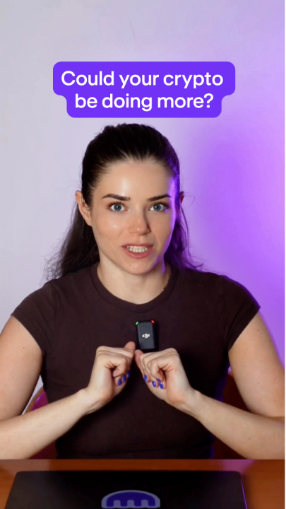 A woman with dark hair holds a small electronic device near her chest, with a purple text overlay reading "Could your crypto be doing more?" at the top of the image. The image, paired with a promotional caption, encourages viewers to use Kraken Earn to make their eligible crypto assets generate returns rather than sitting idle.