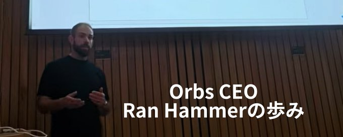 A bearded man speaks in front of a projection screen, with overlaid text reading 'Orbs CEO Ran Hammerの歩み' (The journey of Orbs CEO Ran Hammer).
