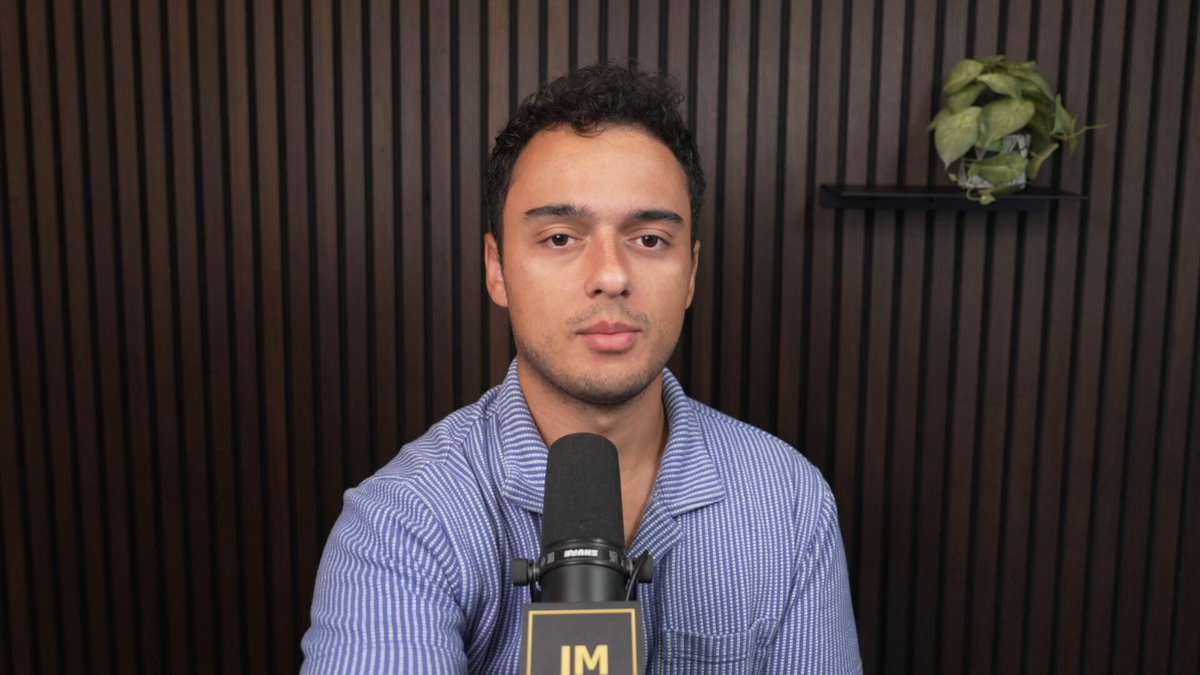 The image shows a man wearing a blue shirt sitting at a microphone with his hands on his lap. The background features a brown wall, which has a plant placed behind him. There is also an audio recording of the man's voice being played back through the microphone. The caption for this image reads "Frontier AI companies are gathering your data, right now I firmly believe this is going to be a MASSIVE problem in the future After chatting with someone much more technical than me, here was my take-away for why $TAO & $VVV & $NEAR are more important than meets the eye".