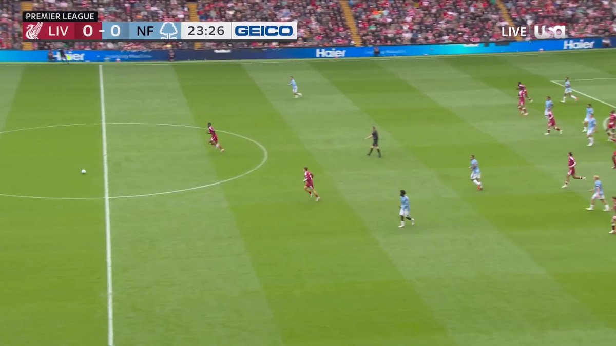 A screenshot of a Premier League soccer match broadcast on USA Network showing LIV 0-0 NF at 23:26, with Liverpool in red and Nottingham Forest in light blue playing on the pitch, sponsored by GEICO.