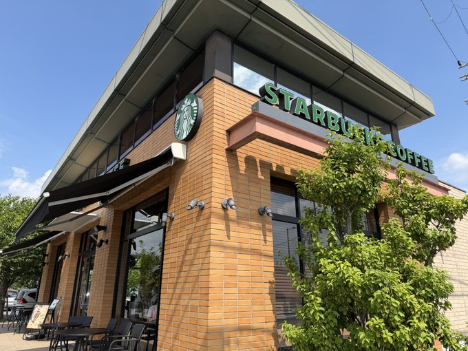 An exterior shot of a Starbucks Coffee location with a brick facade and the green Starbucks logo and signage.