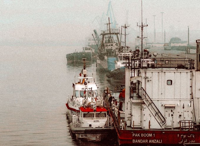 Ships docked at a harbor in Bandar Anzali, with a boat labeled 'PAK BOOM 1' and Persian text visible.