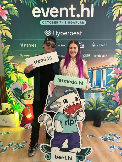 Two people pose at an 'event.hl' (October 7, Singapore) booth with a tropical backdrop; the man holds a 'demi.hl' sign while the woman with purple hair holds a 'letmedo.hl' sign, standing behind a 'beef.hl' mascot.