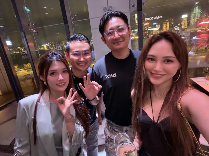 A group of four friends, including @mia_okx who is tagged in the post, poses for a photo in front of a city skyline with a sign of "OKX Wallet" visible. Two of the individuals are making "OK" hand gestures, mirroring the sentiment of the post's message of enduring friendship.