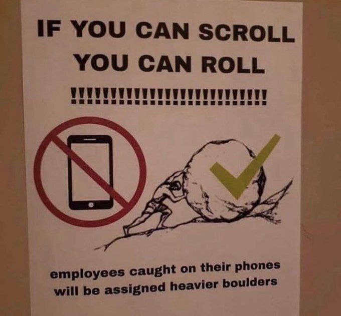 A workplace sign with a humorous tone, featuring a crossed-out smartphone and a drawing of a man pushing a boulder. Text reads: 'IF YOU CAN SCROLL YOU CAN ROLL !!!!!!!!!!!!!!!!!!!!!! employees caught on their phones will be assigned heavier boulders'.