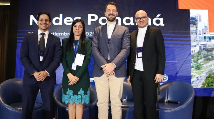 Four professionals pose together at a formal event, with a backdrop displaying "Nodes Panamá" and what appears to be a date in September 2025, alongside an architectural rendering of a high-rise building. The setting appears to be a business or financial conference in Panama, which ties into the post's discussion about Panama's Ministry of Finance working on FATF compliance and virtual asset regulations (Bill 326 for VASP registration).