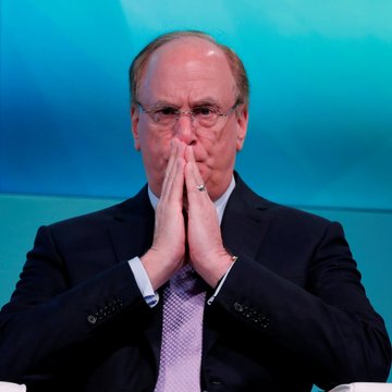 A man in a dark suit and purple tie sits with his hands pressed together against his face in a contemplative or concerned gesture, set against a blue background. The image visually echoes the worry or reflection that might come with news of BlackRock's significant $265.2 million sale of Bitcoin ($BTC).
