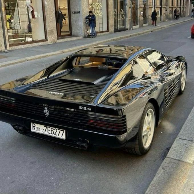 A black Ferrari 512 TR parked on a European street with a Dubai license plate reading 'R DM41 7E6277'.