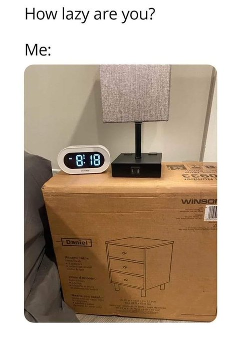 A meme titled 'How lazy are you? Me:' showing an unopened Winsome Daniel nightstand box being used as a side table, with a lamp, digital clock displaying 0:18, and phone charger sitting on top.