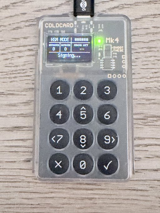 A Coldcard Mk4 hardware wallet displayed on a wooden surface, with its screen showing "HSM MODE," "Signing..." and a green indicator light, illustrating the device being repurposed as an unattended signer for Wasabi Wallet coinjoins.