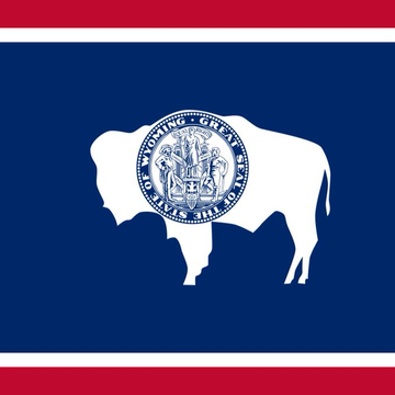The image shows the flag of Wyoming, featuring a white bison silhouette on a blue background with red borders, overlaid with the state seal reading "Wyoming Est. 1890." This flag connects to the post by representing the state of Wyoming, which has adopted Chainlink's Proof of Reserve for its state-issued FRNT stablecoin.